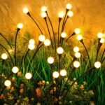 A cluster of ASMAD 6-pack solar firefly garden lights swaying gently in a landscaped garden at dusk.