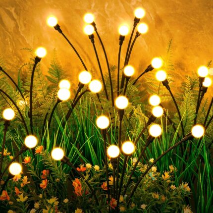 A cluster of ASMAD 6-pack solar firefly garden lights swaying gently in a landscaped garden at dusk.