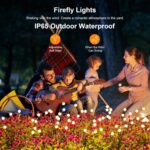 A cluster of ASMAD 6-pack solar firefly garden lights swaying gently in a landscaped garden at dusk.