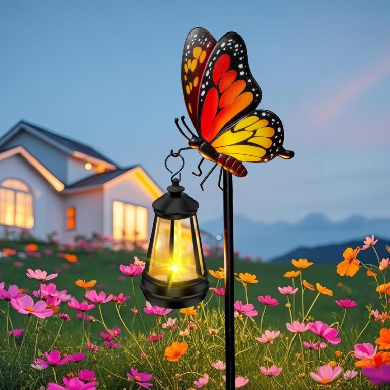A white metal butterfly garden stake with a colorful monarch butterfly and a warm glowing solar light on its antennae, placed