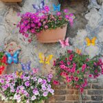 A set of 10 colorful metal butterfly garden stakes with intricate details, standing in a lush green garden bed.