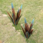 Two colorful Jesokiibo metal agave sculptures, 12 and 16 inches tall, displayed in a vibrant garden setting.