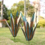 Two colorful Jesokiibo metal agave sculptures, 12 and 16 inches tall, displayed in a vibrant garden setting.