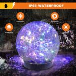 Six MLKNK solar globe lights with cracked glass texture, emitting a multicolor glow, placed in a garden setting.