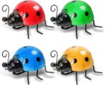 Four colorful metal ladybug sculptures displayed on a garden wall and a green lawn, showcasing their vibrant hues.