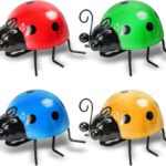 Four colorful metal ladybug sculptures displayed on a garden wall and a green lawn, showcasing their vibrant hues.