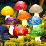 Eight colorful cracked mushroom solar lights staked in a garden bed, glowing with various LED colors.