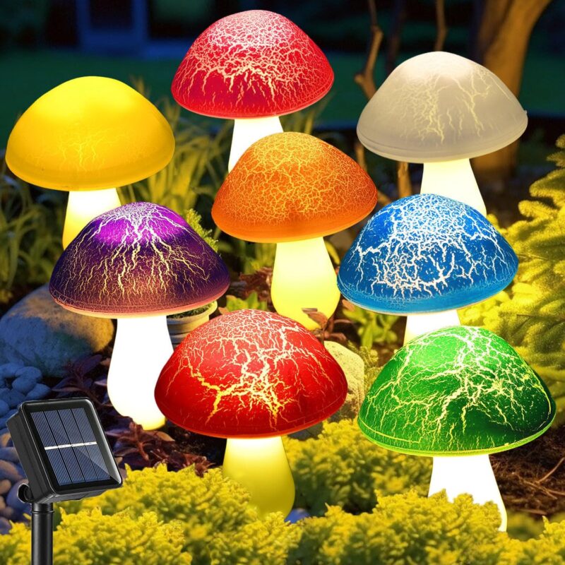 Eight colorful cracked mushroom solar lights staked in a garden bed, glowing with various LED colors.