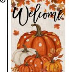 An orange double-sided garden flag featuring a large pumpkin, fallen leaves, and maple leaves, set in an outdoor garden scene