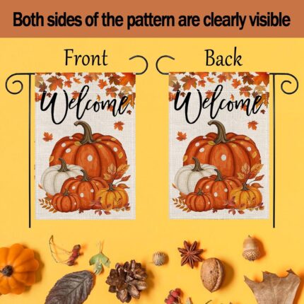 An orange double-sided garden flag featuring a large pumpkin, fallen leaves, and maple leaves, set in an outdoor garden scene